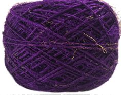 a ball of purple yarn sitting on top of a white surface with lots of thread