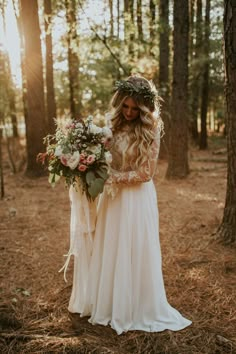 two women standing in the woods with flowers on their head and one holding a bouquet