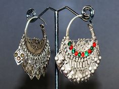 Vintage silver balochi nomad tribal crescent earrings with red and green glass jewels and dangles. The jewels on one earring have probably been replaced. With patina and signs of wear and signs of beeing handmade (like they are not completely symetrical).  The wire is app 1 mm / 0,039 " thick. Weight 18 g both earrings,  Diameter 2,7 cm / 1 ", Length 4,8 cm / 1,89 " Origin: Balochistan/Pakistan Balochistan, often interpreted as the land of the Baloch, is an arid desert and mountainous region in Bohemian Hoop Earrings With Dangling Beads For Festive Occasions, Silver Dangling Charms Earrings For Festival, Silver Festival Earrings With Dangling Charms, Silver Earrings For Festival, Bohemian Chandbali Earrings With Dangling Beads, Green Bohemian Hoop Earrings For Festive Occasions, Traditional Nickel Free Teardrop Hoop Earrings, Traditional Teardrop Hoop Earrings Nickel Free, Traditional Teardrop Nickel-free Hoop Earrings