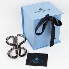 A sophisticated Lanvin Paris modernist clamper bracelet.  This statement piece features an oversized gray steel framing in a futuristic design ornate with black python leather skin. The bracelet is engraved inside: "Lanvin Paris - Made in Italy." The two locking clasps are working perfectly. We will deliver the bracelet with its original branded gift box and label. Measurements: inside across is 2.25 in wide x 1.75 in deep (5.7 x 4.5 cm) - width is 2.75 in (7 cm) - inner circumference is 6.69 in Luxury Rectangular Cuff Bracelet For Formal Occasions, Luxury Metal Evening Cuff Bracelet, Designer Black Cuff Bracelet For Gift, Designer Black Cuff Bracelet As Gift, Luxury Black Metal Cuff Bracelet, Modern Evening Cuff Bracelet, Designer Black Cuff Bracelet For Formal Occasions, Luxury Black Cuff Bracelet, Modern Silver Cuff Bracelet For Evening