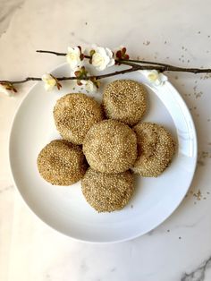 a white plate topped with cookies on top of a marble counter next to a twig