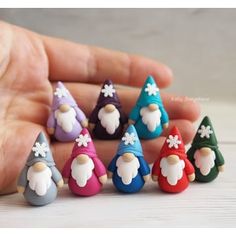 a hand is holding seven small gnomes in different colors