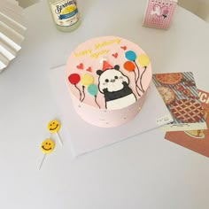 a birthday cake decorated with a panda bear and balloons on top of a white table