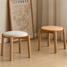 two wooden stools sitting on top of a hard wood floor next to a window