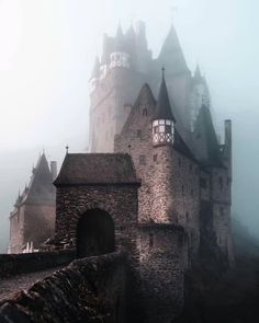 an old castle in the middle of foggy weather with towers and windows on it