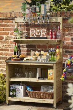 an outdoor bar with bottles and glasses on the top shelf next to a brick wall