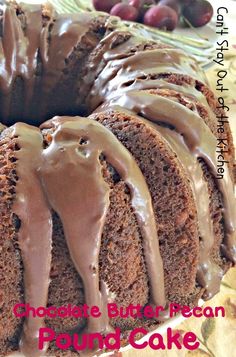 a chocolate butter pecan pound cake with icing on a plate next to grapes