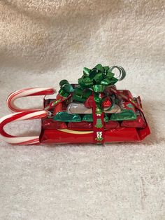 a red sleigh filled with candy canes and wrapped in green ribbon on top of a white blanket