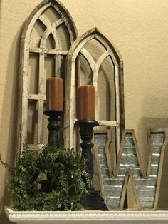 two candles sitting on top of a mantle next to an old window with the letter w