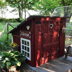 a small red shed sitting in the middle of a yard next to a fence and trees