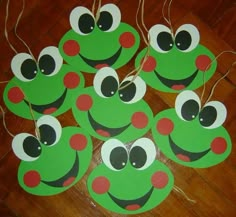 some green and red paper cut outs with eyes on them sitting on a wooden floor