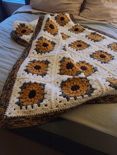 a crocheted blanket with sunflowers on it is laying on a bed