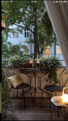 an outdoor table with two chairs and a lit candle on it in front of a window