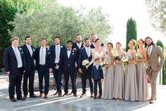 a group of people standing next to each other in front of an olive tree filled field