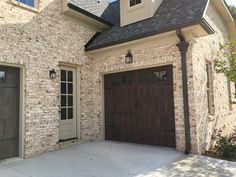 a brick house with two brown garage doors