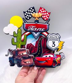 the hand is holding up a card with cars on it and other magnets attached to it