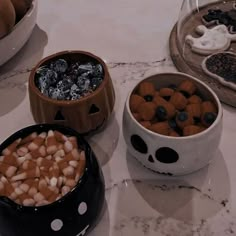 three bowls filled with candy and marshmallows on top of a marble counter