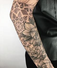 a woman's arm with flowers on it and an intricate pattern in the background