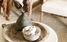 a white table topped with a vase and bowl