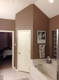 a bath tub sitting next to a white door in a room with brown walls and carpet