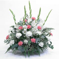 a bouquet of white and pink carnations in a basket with greenery on the side