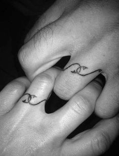 two hands holding each other with tattoos on their fingers and the words love are written in cursive letters