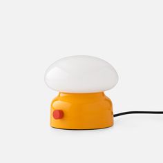 an orange table lamp with a white light on it's side and a black cord