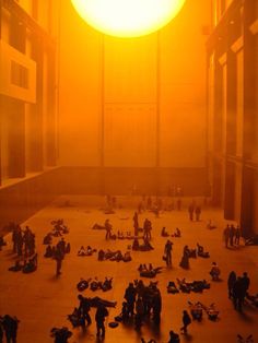 people are sitting and standing in the middle of a large room with yellow light coming from it