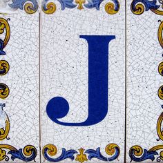 the letter j is made up of blue and white tiles with gold designs on them