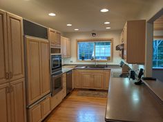 an empty kitchen with wooden cabinets and stainless steel appliances in the middle of the room