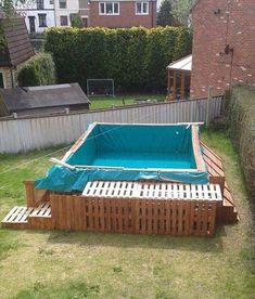 an above ground pool in the backyard with a wooden deck and fence around it, surrounded by grass