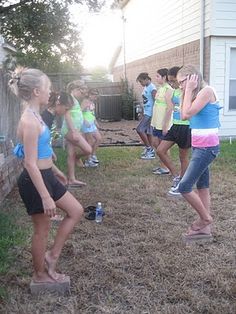 a group of young people standing around each other in the yard talking on their cell phones