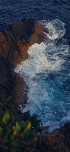 an ocean view with waves crashing on the rocks