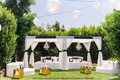 an outdoor seating area is decorated with white linens and drapes for the canopy