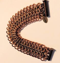 Handcrafted of bronze and copper, our luxe cuff-style bracelet offers a captivating combination of classic European 4-in-1 weaving and contemporary style. An eye-catching shimmer of warm gold provides a touch of refinement, guaranteeing this stylish statement piece will get lots of attention. 16 gauge bronze and copper jump rings woven with the bronze center stage flanked by copper rings. Shown here in the first three photos with light to deeper color backgrounds to highlight the subtle contrast in the metals.Finished with an antique copper magnetic slide clasp.Measures 7 inches overall. * Signature SUZANNA charm. * Arrives in a black satin drawstring storage pouch. * To inquire about this product please click Ask a Question on our website or convo on our Etsy Shop. * In stock and ready to Elegant Brown Metal Cuff Bracelet, Bronze Copper Bracelets For Jewelry Making, Elegant Gold-colored Copper Bracelets, Elegant Gold-colored Copper Bracelet, Adjustable Gold Chainmail Jewelry, Elegant Metal Chain Bracelet With Jump Ring, Elegant Gold Copper Cuff Bracelet, Chain Maille Bracelet, Color Backgrounds