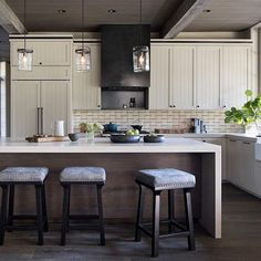 two stools sit at the center of a kitchen island with white cabinets and gray countertops