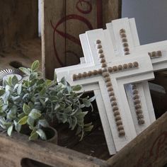 a cross sitting on top of a wooden box next to a potted plant in front of it