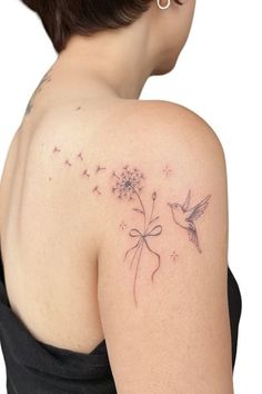 the back of a woman's shoulder with a dandelion tattoo on it