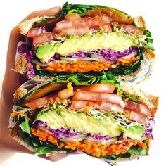 two sandwiches with meat, lettuce, and other toppings are stacked on top of each other