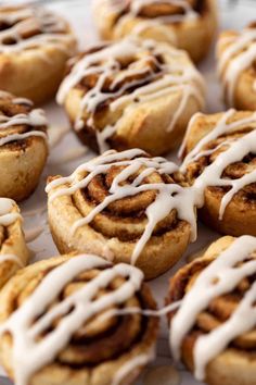 cinnamon rolls with icing sitting on a baking sheet