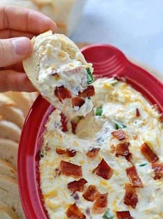 a person dipping some food into a red bowl with crackers on the side to eat it