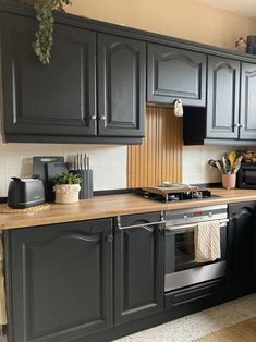 a kitchen with black cabinets and wooden counter tops, an oven and dishwasher