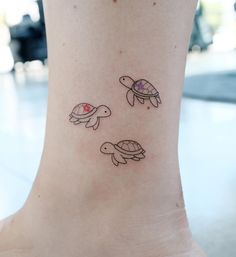 a small tattoo on the ankle of a woman's foot with three turtles swimming around