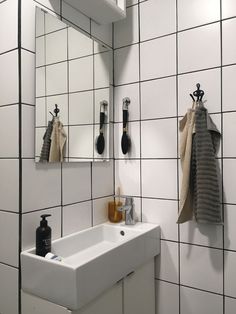 a white sink sitting under a bathroom mirror next to a wall mounted faucet