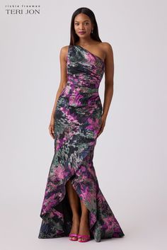 a woman wearing a purple and black dress with one shoulder, high slit skirt and floral print