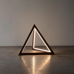 an illuminated sculpture on the floor in front of a white wall with light coming from it