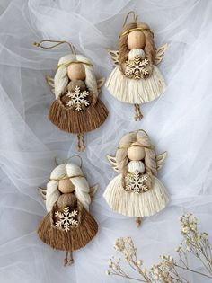 four angel ornaments hanging from strings on a white background with tulle and snowflakes