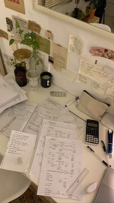 a cluttered desk with many papers on it and a cell phone sitting next to it