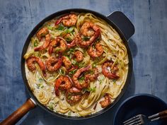 a pan filled with pasta and shrimp on top of a table