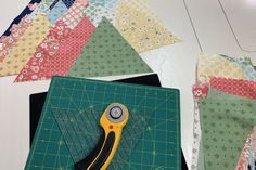 a pair of scissors sitting on top of a cutting board next to some quilts